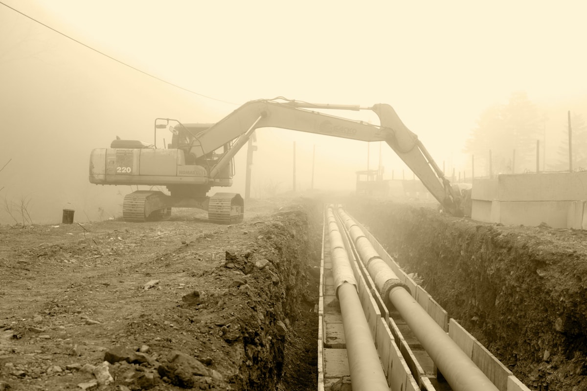 Excavator digging a trench to locate and access underground pipeline
